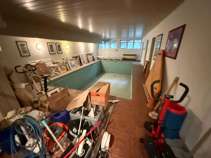 Zona de piscina interior llena de objetos y cajas antes del vaciado en Tenerife