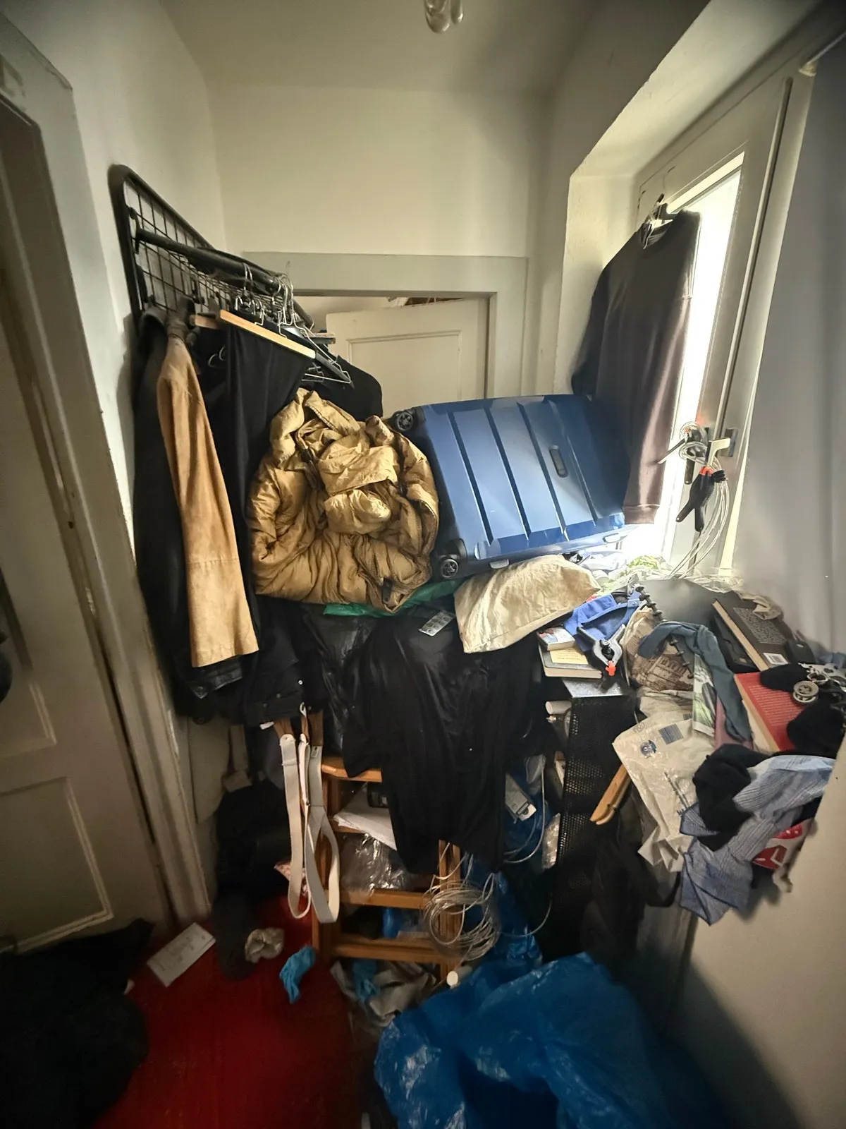 Vivienda afectada por síndrome de Diógenes en Maspalomas — pasillo saturado de ropa y objetos acumulados antes del vaciado profesional